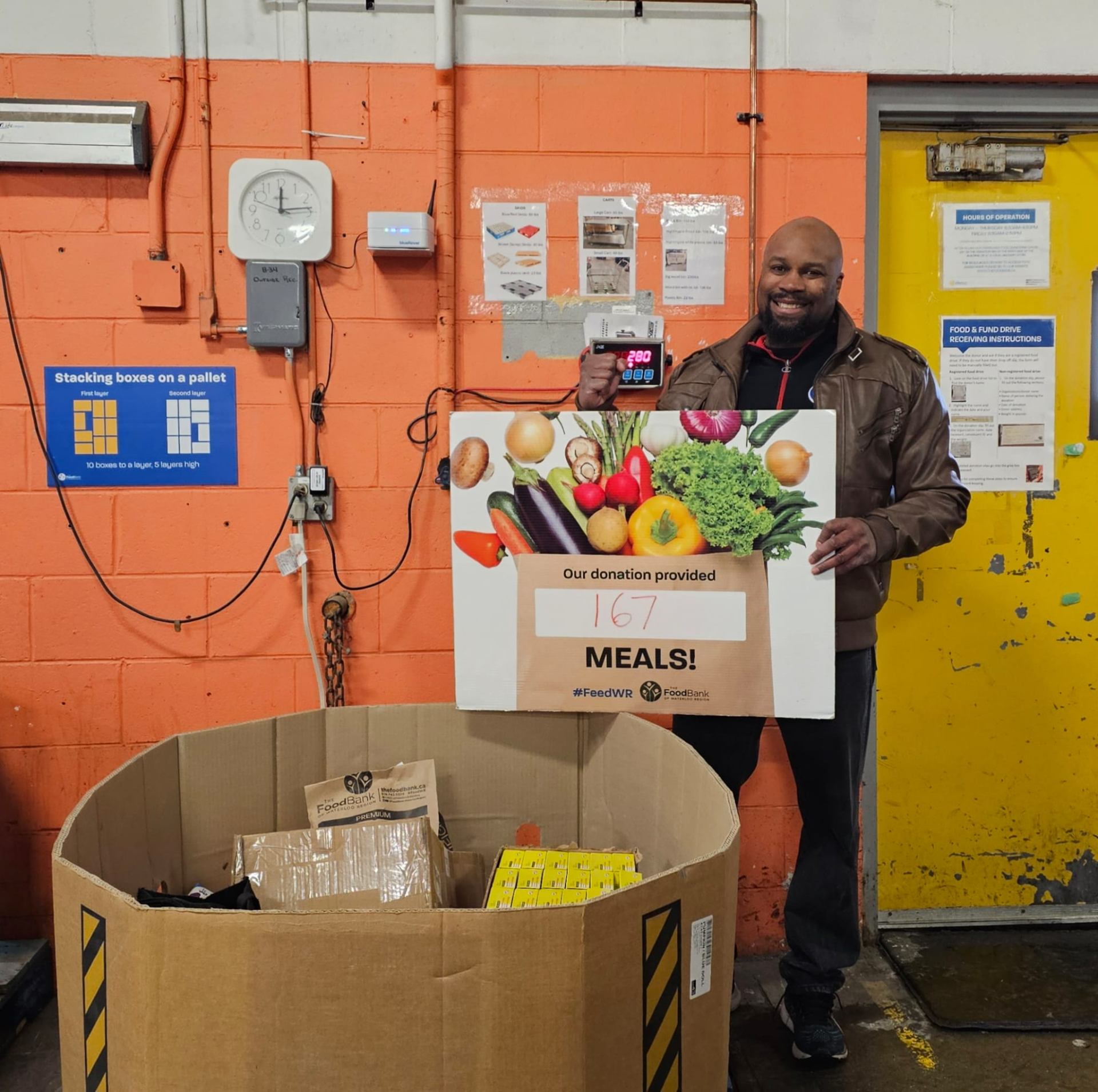 Fitz at The Food Bank of Waterloo Region holding a sign showing his donation provided 167 meals to local families