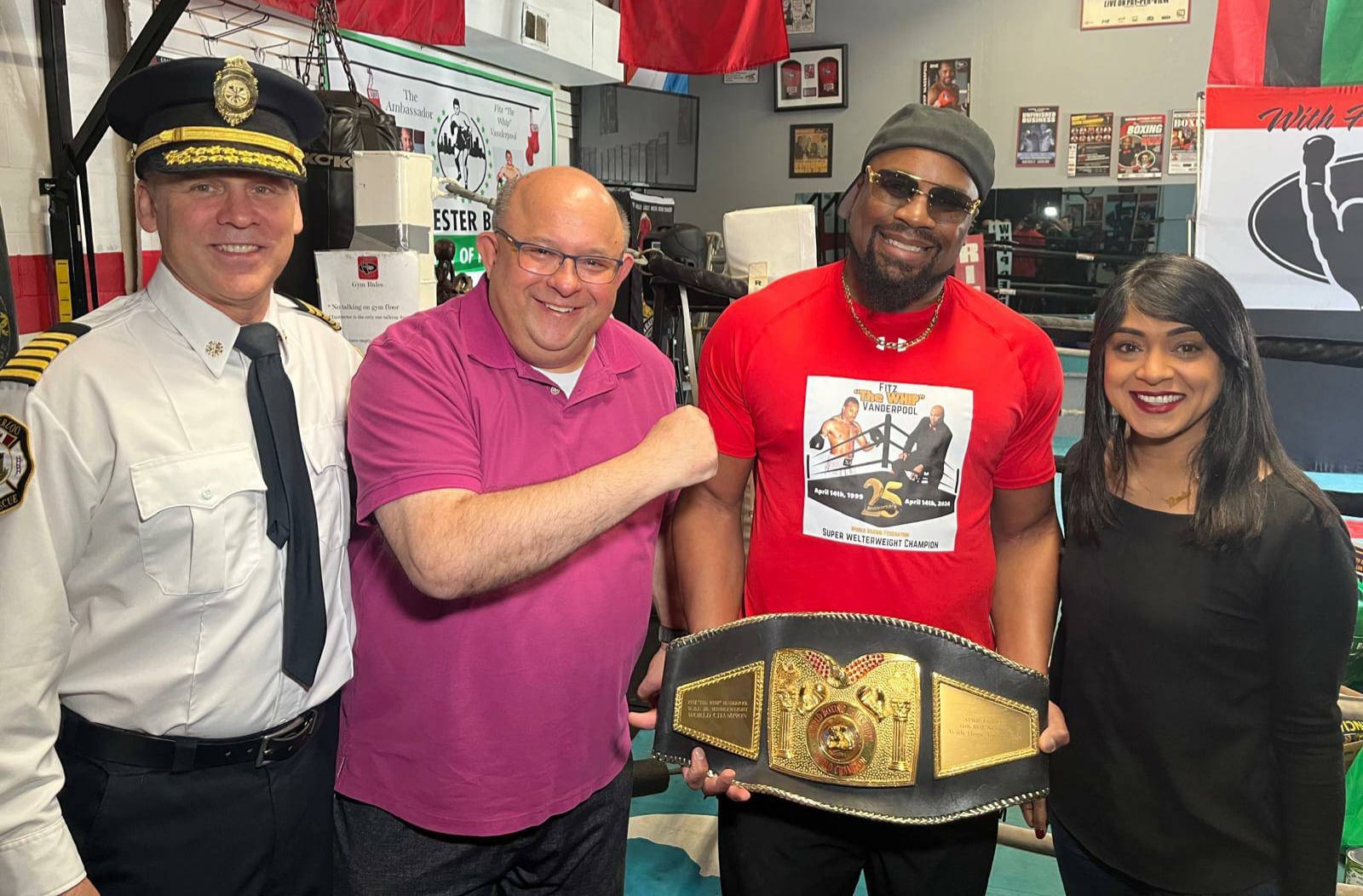 Fitz with Kitchener fire chief, a community supporter and MP Bardish Chagger at The Whip Boxing Academy, holding his World Boxing Federation Super Welterweight championship belt