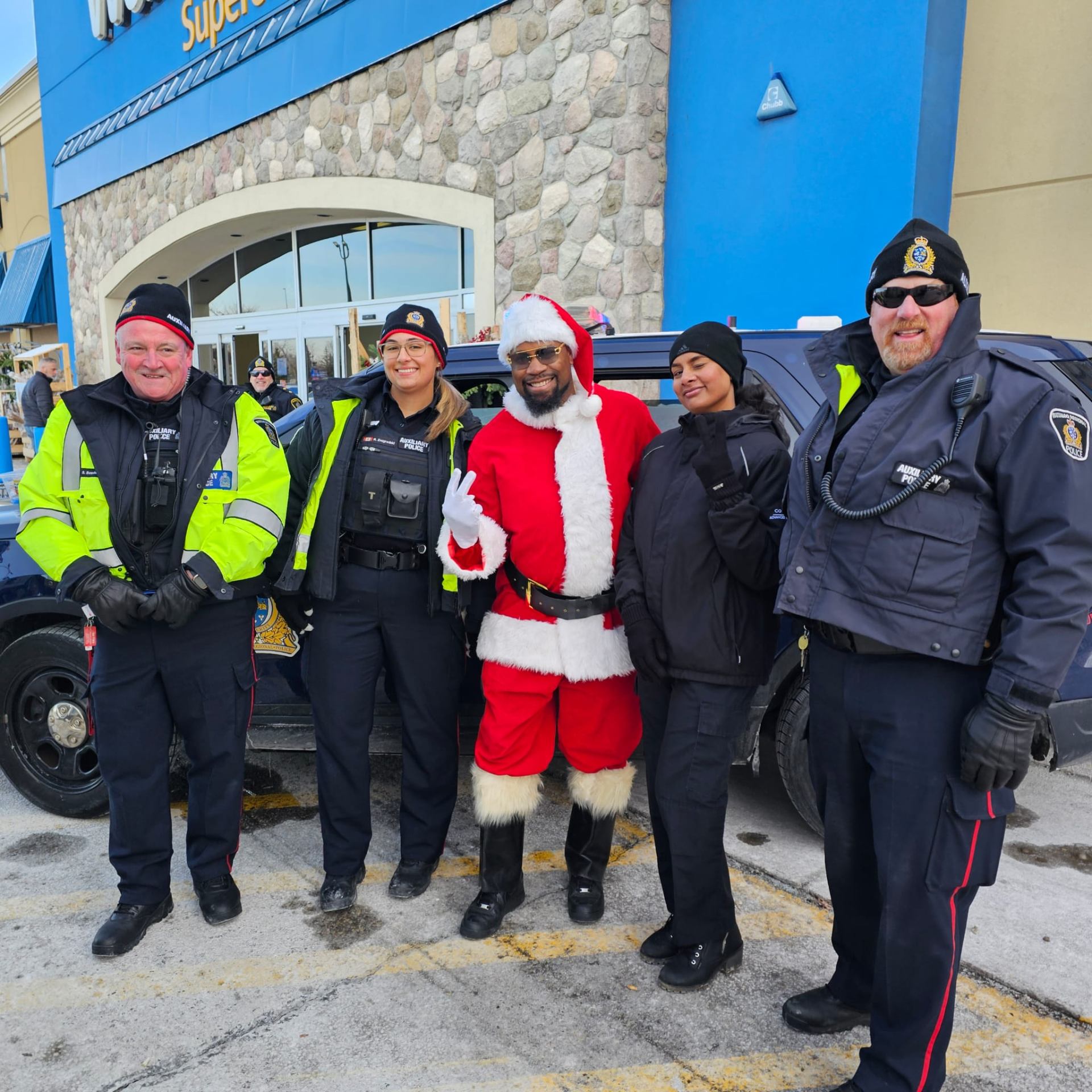 Fitz as Santa standing with Waterloo Regional Auxiliary Police officers at a community Stuff-A-Cruiser toy drive
